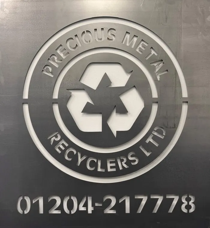 Brushed steel plate with the Precious Metal Recyclers roundel and telephone number 01204 217778 embossed into it